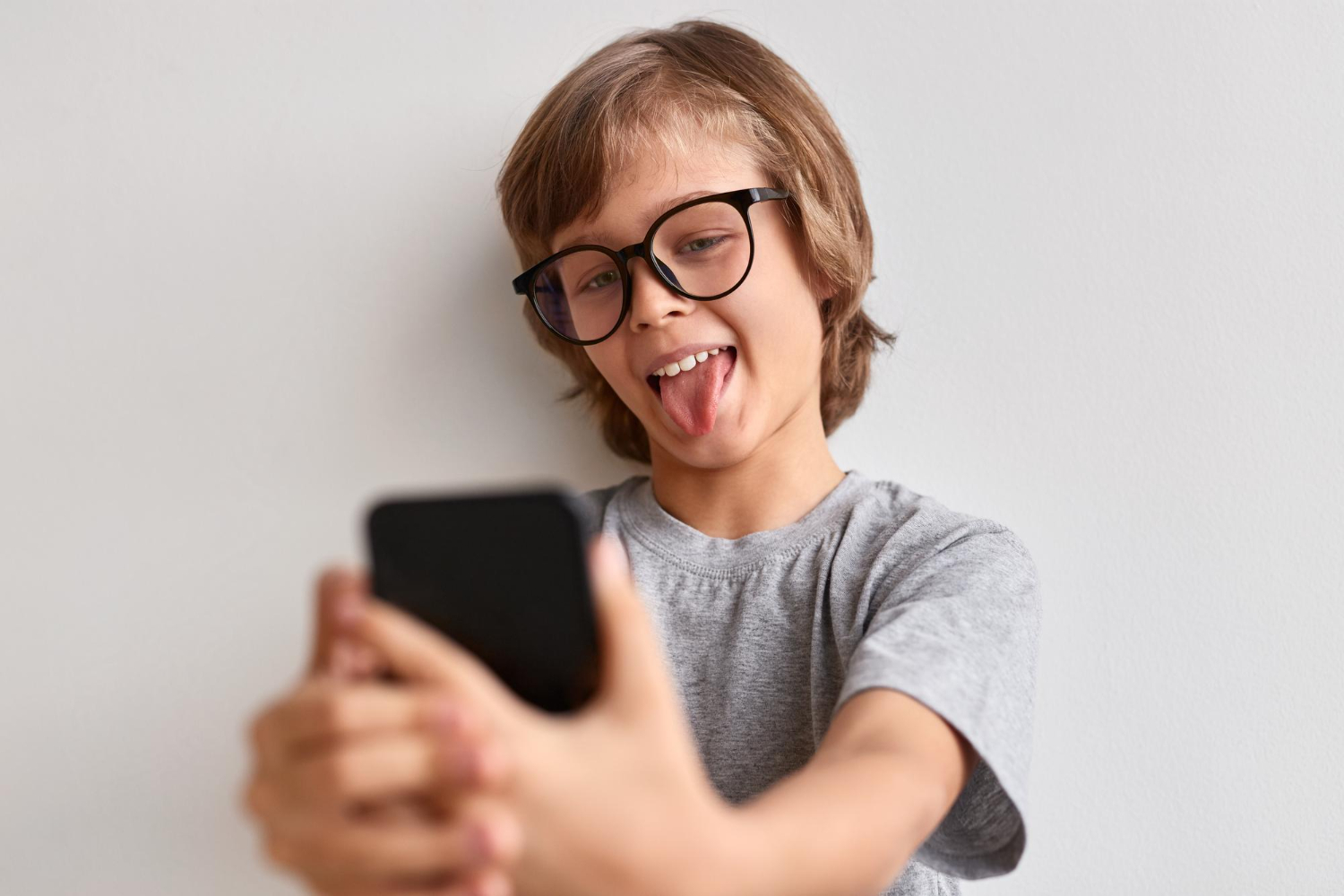 anak berkacamata mengambil selfie di ponsel pintar